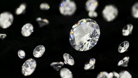 Real-big-brilliant-cut-glittering-diamond-surrounded-by-the-smaller-ones-rotating-clockwise-in-shallow-depth-of-field-on-the-black-table---cinematic-selective-focus-close-up-shot