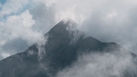 Clouds-reveal-high-peak-of-volcano-mountain-in-Guatemala,-handheld-view