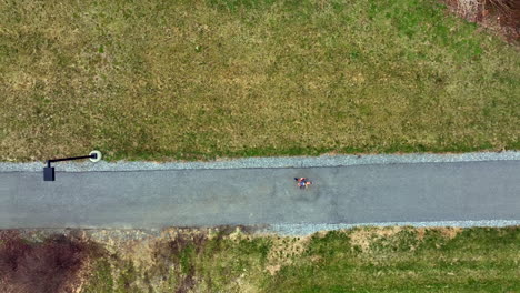 Slow-motion-top-down-aerial-of-woman-running-on-paved-trail-and-into-tunnel