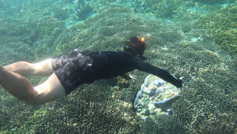 POV-shot-of-young-attractive-man-diving-down-and-snorkeling-in-tropical-ocean-water-with-beautiful-coral-reef
