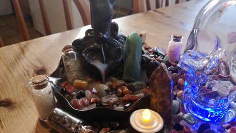 Backflow-incense-collection-of-colourful-healing-crystals-and-mysterious-spiritual-skull-on-wooden-kitchen-table