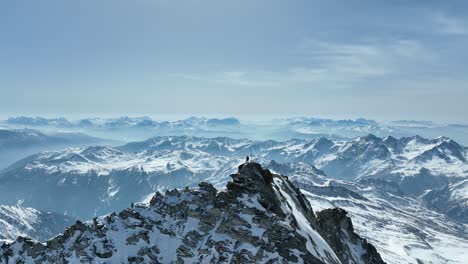 Drohnenaufnahme-Einer-Person,-Die-Auf-Einem-Felsigen-Gipfel-In-Den-Alpen-Steht