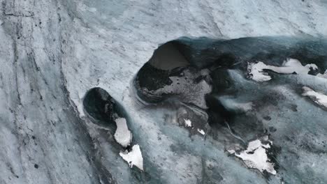 Ascending-top-down-shot-of-blue-colored-Ice-Cave-Glacier-and-flowing-water-in-Iceland