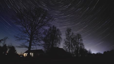 Mehrere-Sterne-Umkreisen-Den-Klaren-Himmel-Hinter-Den-Hohen-Bäumen,-Während-Die-Nacht-über-Eine-Litauische-Landschaft-Hereinbricht