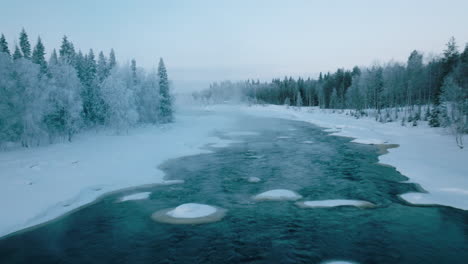 Nebel-über-Dem-Eiskalten-Wasser-Des-Vikakongas-flusses,-Der-Im-Winter-In-Finnland-Durch-Verschneite-Wälder-Fließt