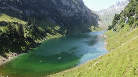 Falensee-Mountain-Lake-at-Swiss-Alps-in-Switzerland---Aerial-Drone-View-of-People-Walking-and-Swimming-in-the-Blue-Emerald-Lake