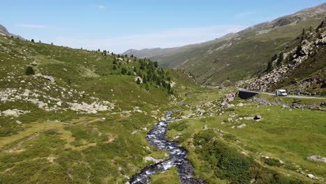Swiss-National-Park---Aerial-Drone-View-of-the-Green-Mountain-Valley,-Streaming-River-and-Scenic-Road