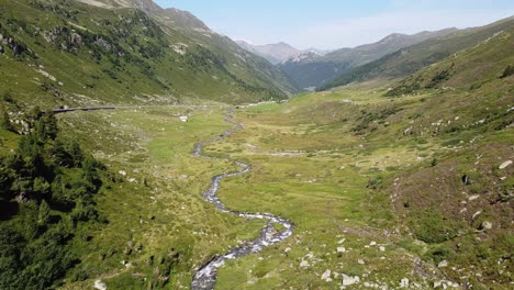 Parque-Nacional-Suizo,-Suiza---Vista-Aérea-De-Drones-Del-Valle-Verde-De-La-Montaña,-Río-Que-Fluye-Y-Carretera-Escénica-Durante-El-Verano
