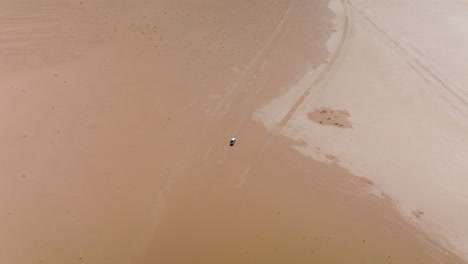 Desolate-Landscape-With-4x4-Vehicle-Driving-Across-Wadi-Rum-Desert-In-Jordan