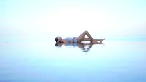 A-woman-lies-on-her-back-in-the-shallow-end-of-an-infinity-edge-pool-giving-the-illusion-she-is-floating-in-midair