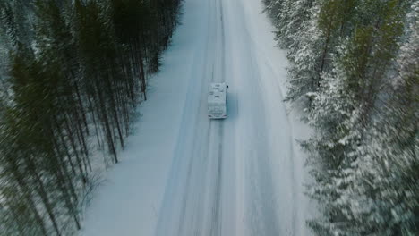 Tracking-Shot-Of-A-Camper-Van-Driving-On-Snowy-Road-In-Lapland,-Finland