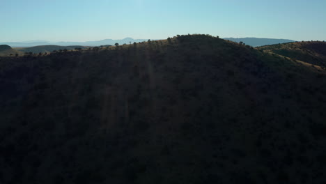 Aerial-coming-over-ridge-revealing-remote-road-through-desert-landscape,-4K