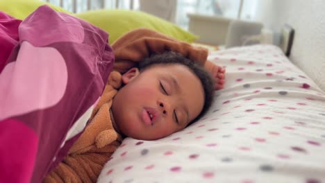 Bebé-Afroeuropeo-Exótico-De-Dos-Años-Durmiendo-Profundamente-En-Su-Cama-Usando-Un-Pijama-Marrón-De-Invierno