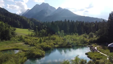 Zelenci-Nature-Reserve-at-Slovenia---Aerial-Drone-View-of-the-Blue-Emerald-Lake,-Wooden-Boardwalks-and-High-Mountains