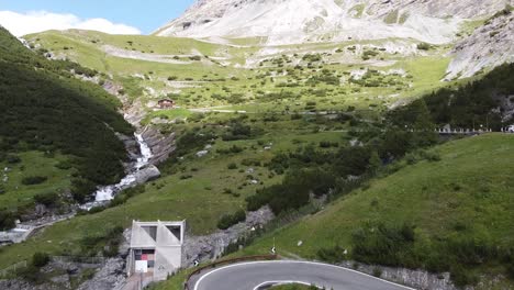 Stelvio-Mountain-Pass-at-South-Tyrol,-Italy---Aerial-Drone-View-of-a-MotorCycle-driving-the-Famous-Road-with-Curves-and-Hairpins---Giro-d'-Italia-Cycling-Lap