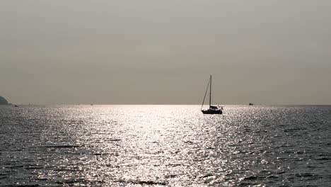 An-Isolated-Yacht-on-the-Horizon-with-Sunlight-Reflecting-on-the-Calm-Waters-off-the-Coast-of-Bangsaray-near-Pattaya,-Thailand