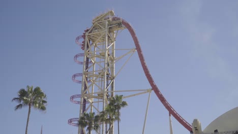 Beautiful-wide-shot-of-a-roller-coaster-climbing-a-steep-lift-hill,-and-then-plunging-down-the-large-drop