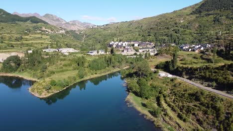 Sallent-de-Gallego-at-Tena-Valley,-Huesca,-Aragon,-Spanish-Pyrenees,-Spain---Aerial-Drone-View-of-the-Mountain-Village,-Lake-Embalse-de-Bubal-and-Motorhomes