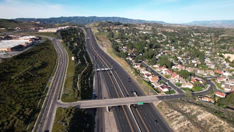 Flying-over-a-freeway-through-Antelope-Valley's-picturesque-suburb-in-Los-Angeles-County,-California