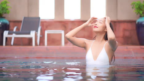 A-sexy-attractive-woman-pushes-back-her-wet-hair-from-her-face-while-in-a-swimming-pool