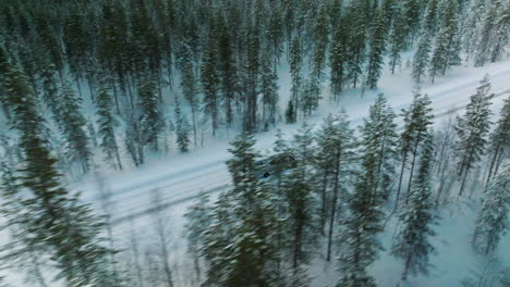 Camper-Van-Driving-Through-Thick-Forest-In-Winter-in-Lapland-Finland---aerial-shot
