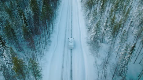 Weißer-Camper,-Der-Auf-Verschneiter-Straße-In-Lappland,-Finnland,-Fährt---Luftaufnahme