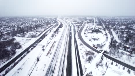 Snow-covered-highway-through-dense-suburban-residential-area