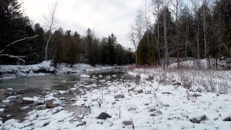 Frozen-rocky-river-bank-with-light-dusting-of-snow