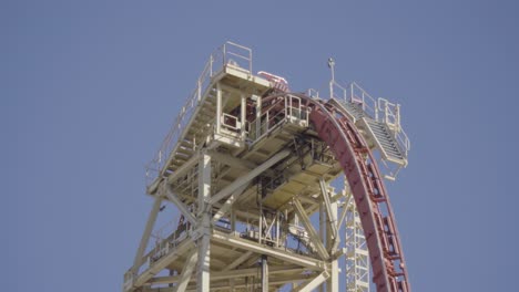 Epic-close-up-shot-of-a-roller-coaster-gliding-over-the-lift-hill,-and-then-plunging-down-a-large-drop