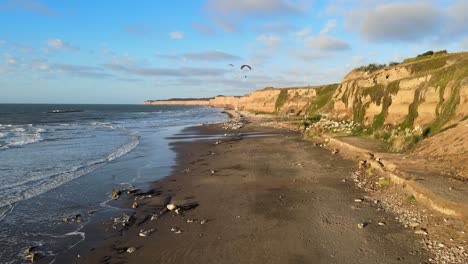 Flying-over-cliffs-beach-with-paragliding-flights,-Argentina