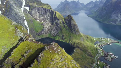 Flying-next-to-two-person-standing-at-the-mountain-top-in-Lofoten-Norway