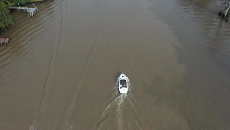 Drone-following-a-motorized-boat-crossing-a-jet-ski-on-a-dirty-brown-water-river
