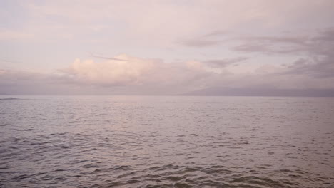 Überblick-über-Meereswellen,-Die-Sich-Nach-Sonnenuntergang-An-Einem-Sandstrand-Mit-Bergsilhouette-Im-Hintergrund-Waschen