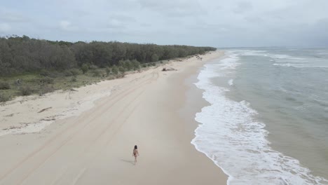 Isolierte-Ansicht-Einer-Frau,-Die-Auf-Der-Sandigen-Küste-In-North-Stradbroke-Island,-Queensland,-Australien,-Spazieren-Geht