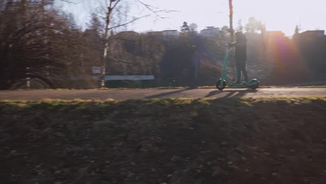 A-little-boy-rides-fast-through-a-sunny-city-park-on-an-electric-scooter
