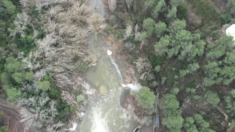 Backward-drone-flight-over-a-medium-size-dam-in-Castellon,-Spain