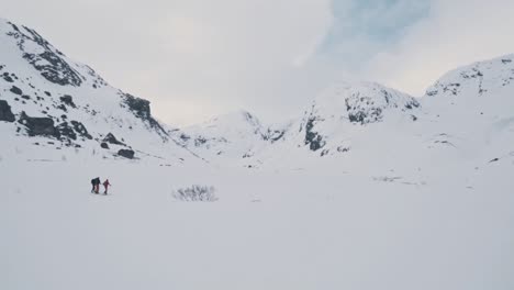 Pareja-De-Excursionistas-Escalando-La-Ladera-De-Una-Montaña-Nevada-En-Noruega,-Vatnahalsen