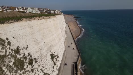 People-Walking-on-Path-by-Rottingdean-Sea-Cliffs-in-Brighton,-UK---Aerial
