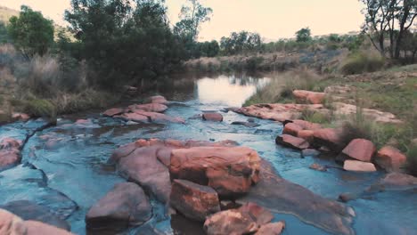 Rocky-ford-over-small-river-in-african-landscape,-backward-dolly-shot