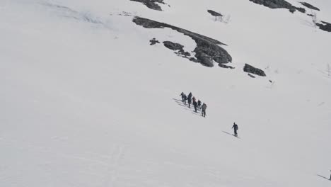 Group-of-hikers-climbing-up-snowy-mountain-in-Norway,-Vatnahalsen-region
