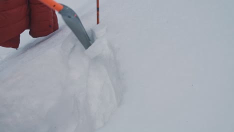 Hiker-digging-snow-layer-to-check-snow-profile-for-avalanche-danger,-close-up-view