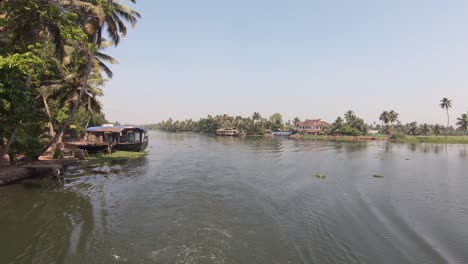 View-from-sailing-boat-of-inhabited-river-shores-at-Alappuzha-or-Alleppey,-India