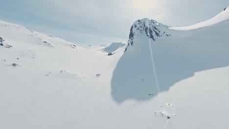 Esquiadores-Haciendo-Senderismo-En-Un-Paisaje-Montañoso-Nevado-En-Un-Día-Soleado,-Paisaje-Noruego