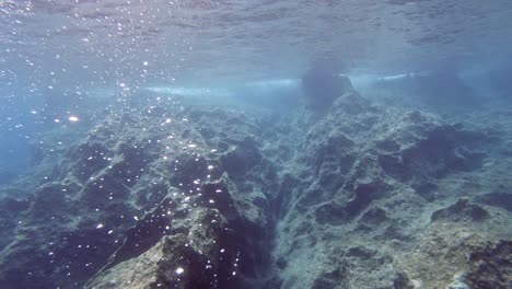 Underwater-Rocky-Seafloor-And-Formed-Bubbles-In-The-Blue-Waters-Of-Paralia-Emplisi,-Greece