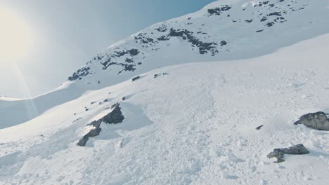 High-snow-covered-mountain-slope-in-Norway-with-avalanche-debris,-aerial-FPV-view