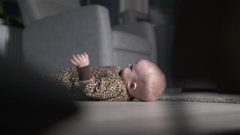 Baby-girl-in-onesie-plays-on-living-room-floor