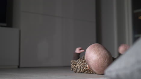 Close-up-of-Caucasian-baby-in-leopard-jumpsuit-rolling-over-itself-on-floor