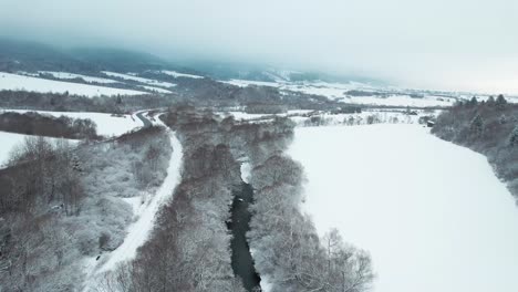 Paisaje-Aéreo-De-Invierno-Blanco-En-El-Parque-Nacional-De-Tatra-Eslovaquia-Destino-Natural-De-Vacaciones-Para-Esquiar,-Drone-Sigue-Río-Helado-En-Naturaleza-No-Contaminada