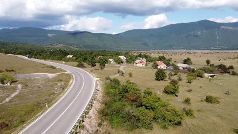 Touring-Bus-Driving-the-Road-to-Plitvice-National-Park,-Croatia---Aerial-Drone-View-of-Inland-with-Green-Valley-and-Farms