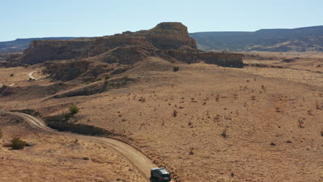 Aerial-passing-over-4x4-car-driving-through-scenic-desert-landscape